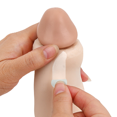 【使用手順２】余皮を剥いて亀頭を露出させたら、剥離紙のない方の端をカリ下あたりに貼り付け、手で押さえます。